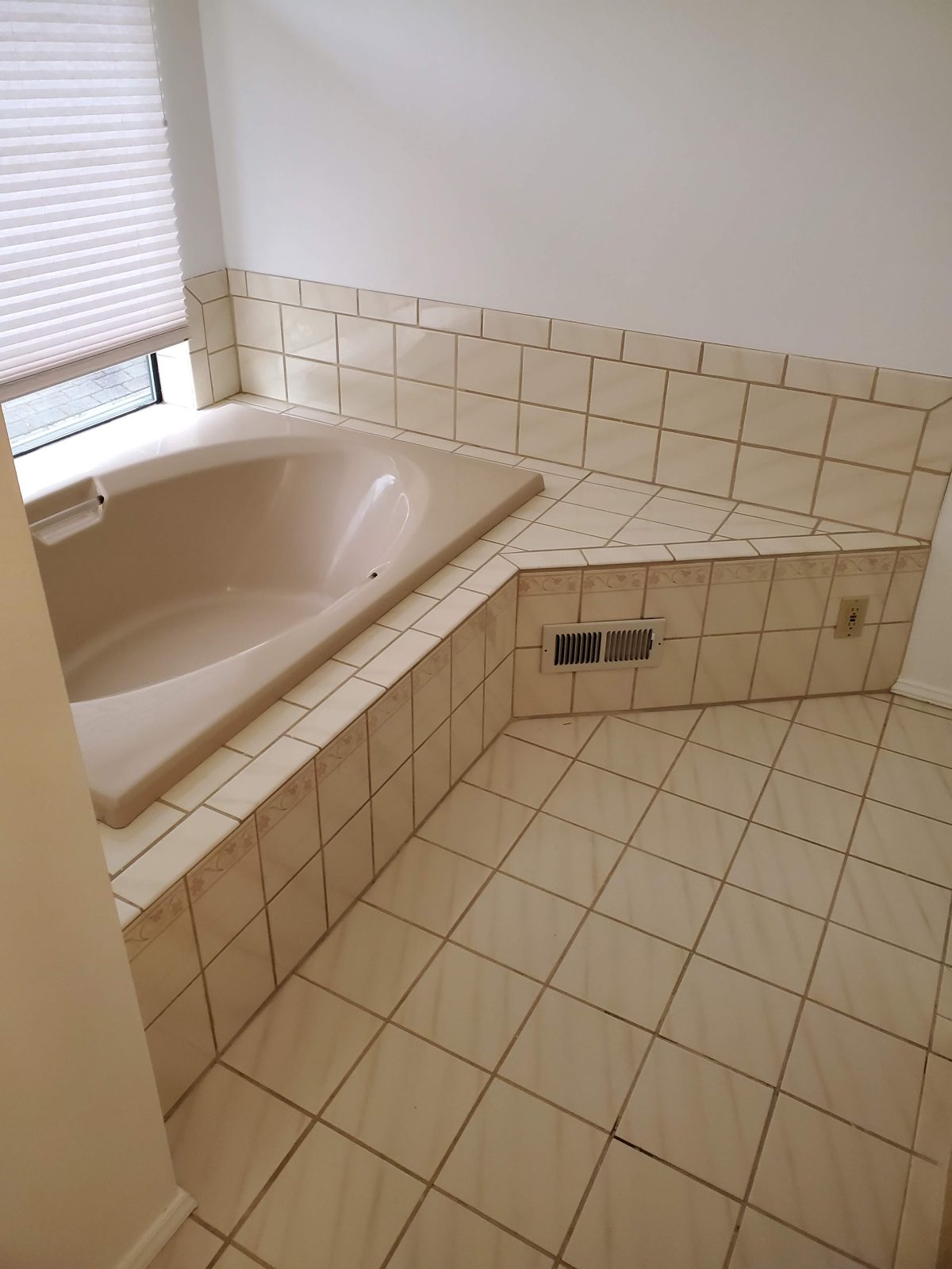 Dated 1990s bathroom with almond tile garden tub